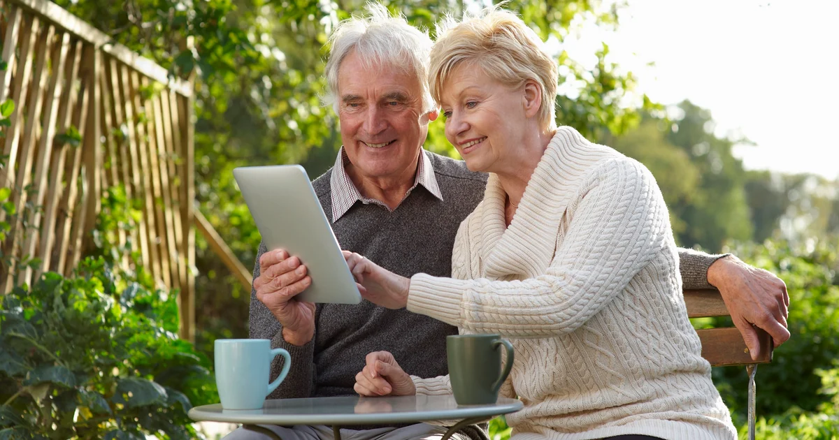 Casal sênior sorrindo e planejando o futuro no tablet, no jardim